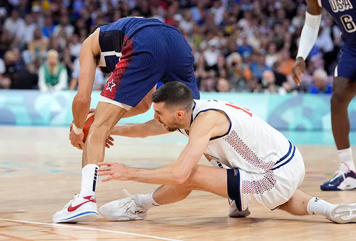 Serbia shooting guard Ognjen Dobric (13) and United States guard Devin Booker (15) fight for a loose ball in the first quarter during the Paris 2024 Olympic Summer Games at Stade Pierre-Mauroy.