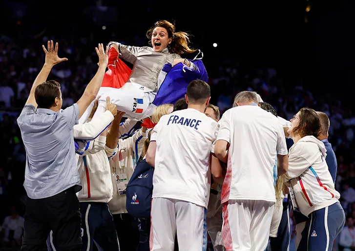 Gold medalist Manon Apithy-Brunet (FRA) and silver medalist Sara Balzer (FRA) are hoisted in the air by their team after the women's sabre gold medal bout during the Paris 2024 Olympic Summer Games at Grand Palais on July 29, 2024.